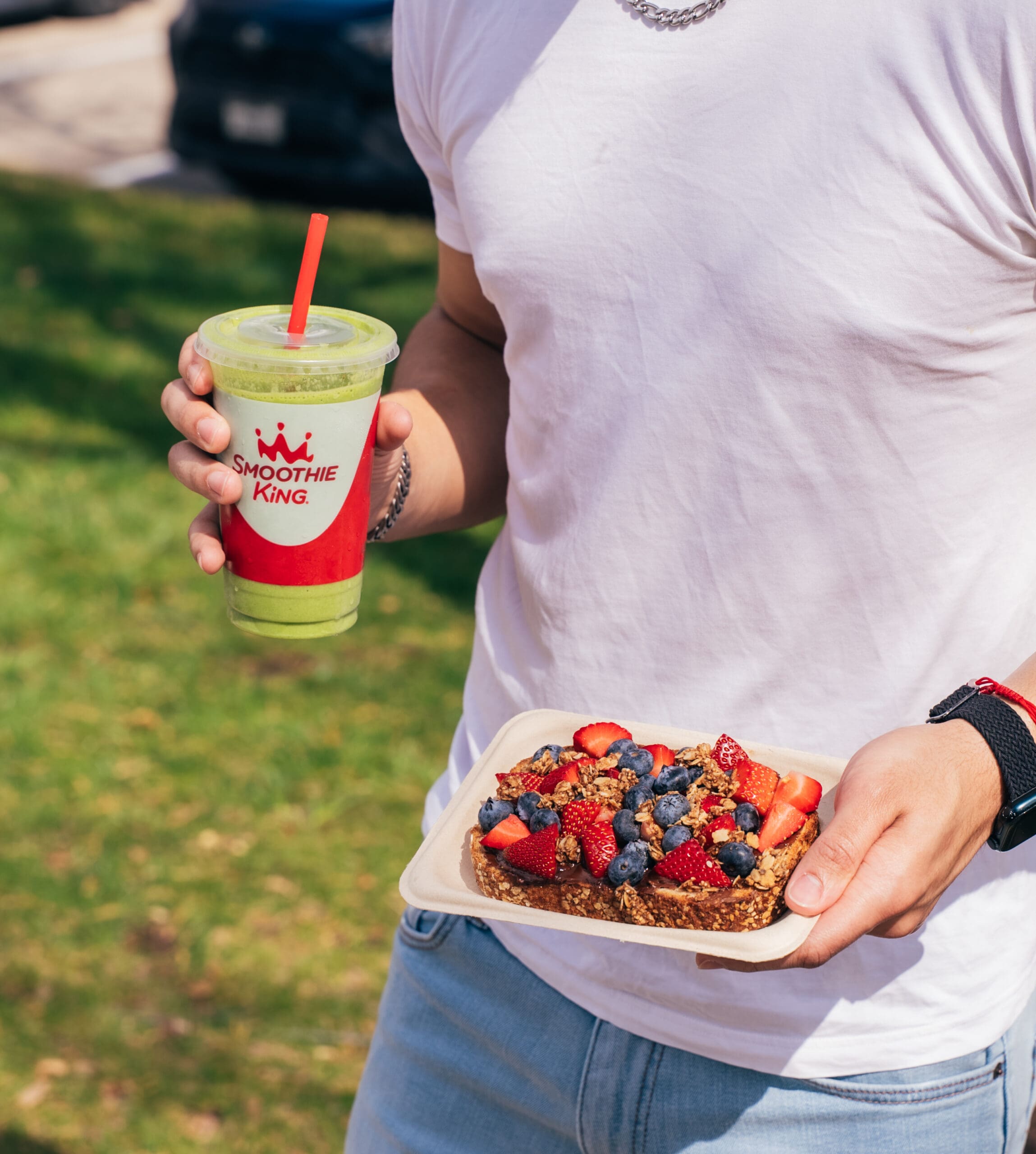 A man focusing on nutrition for busy schedules while holding a Smoothie King smoothie and Loaded Toast