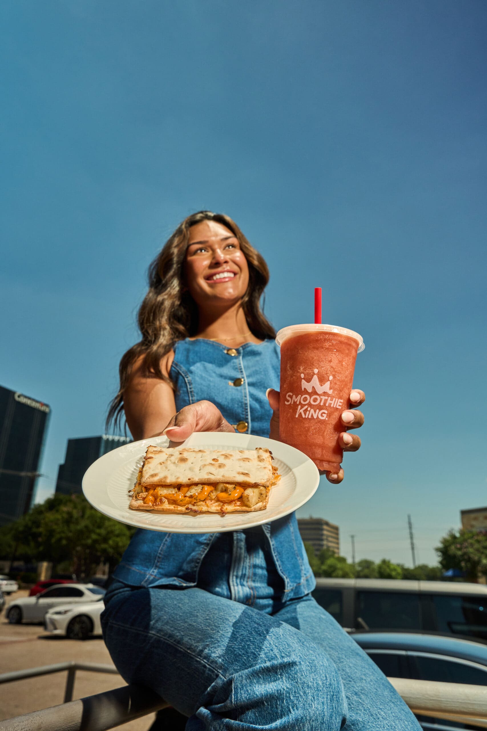 A woman holding a Smoothie King flatbread and smoothie.