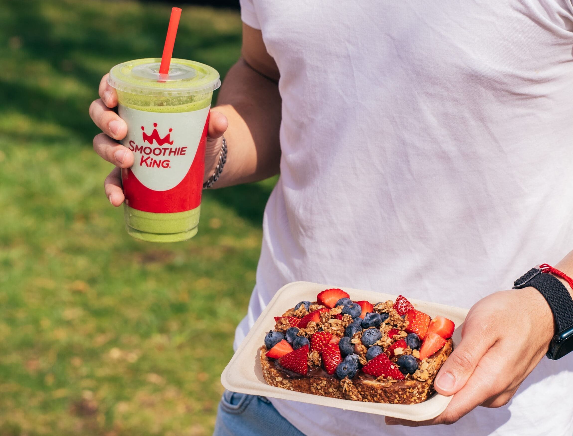 A person holding their smoothie and Loaded Toast from Smoothie King