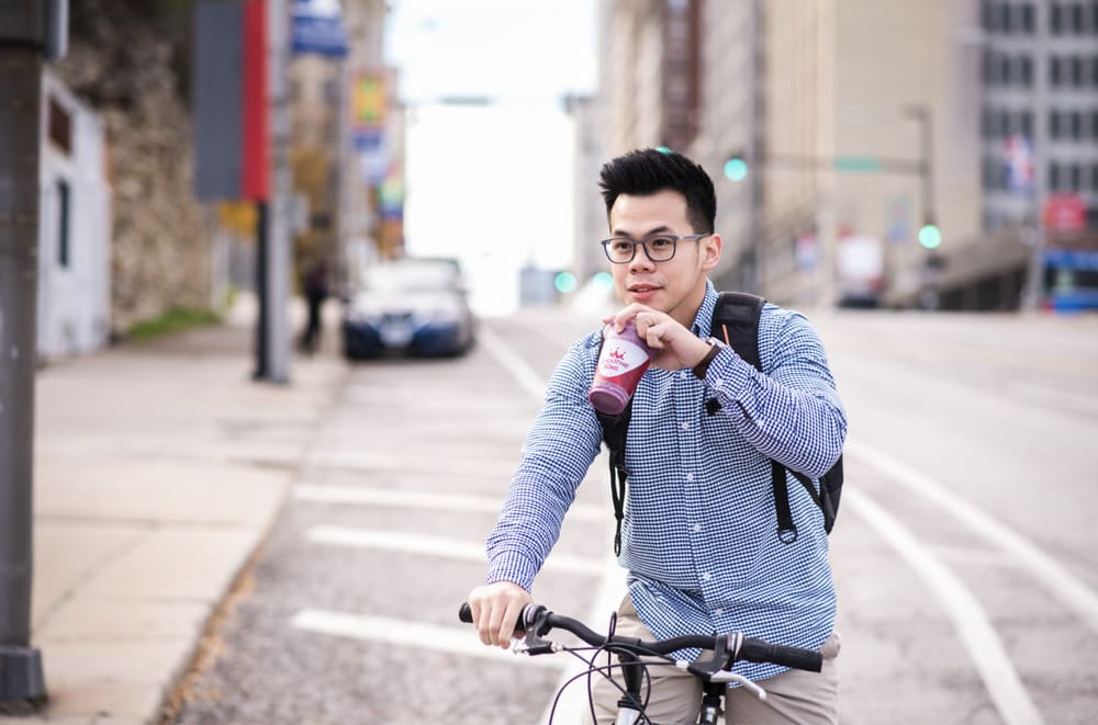 Man on a bike on a city street drinks a Smoothie King smoothie